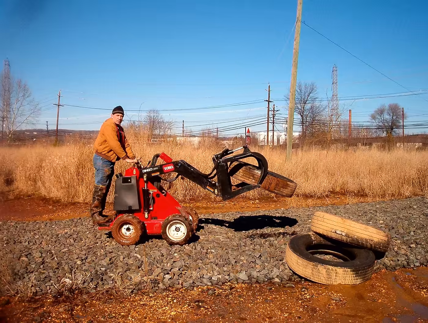 A staff member loading discarded tires, a common mosquito breeding source, into a grapple.