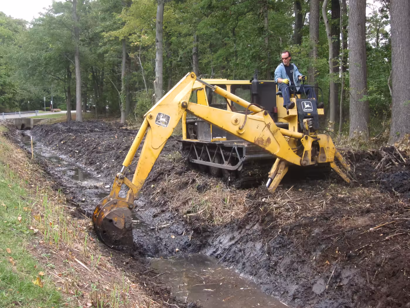 An excavator clearing a drainage ditch during water management work.